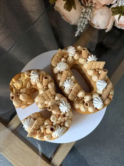 Number 40 cake with golden layers, caramel-coloured cream, white meringues, wafer rolls, blonde chocolate bars, biscuit crumbs and metallic gold sugar pearls.