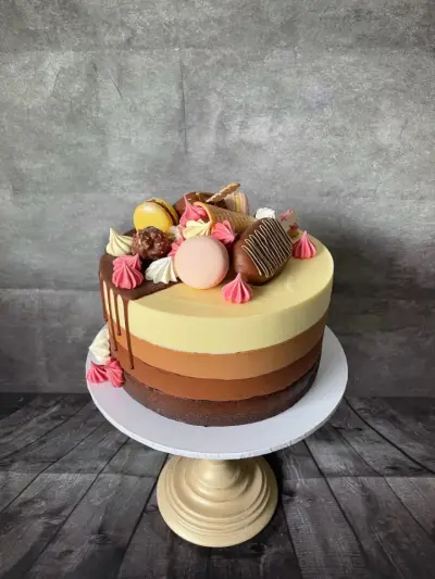 Four-tone chocolate ombre cake with a dark chocolate drip, topped with truffles, macarons, wafers and meringue kisses.