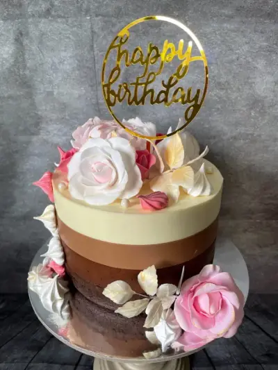 Four-tone ombre cake topped with pink and white sugar roses, meringue kisses, and a gold Happy Birthday topper.