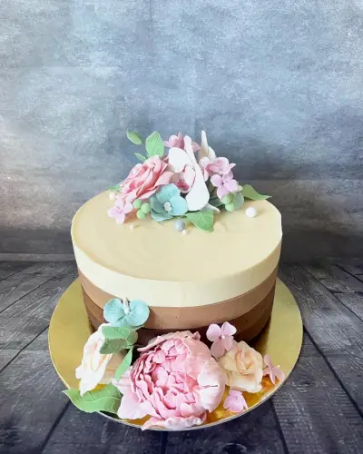 Cream-to-chocolate ombre cake decorated with pink and cream sugar flowers, mint blooms and green leaves.