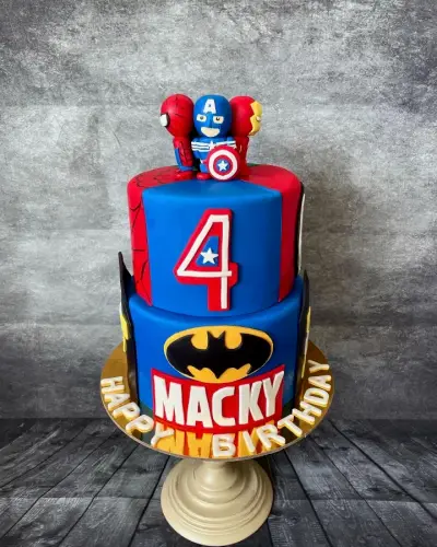 Two-tier blue and red cake with fondant superhero figures on top, a number 4, a Batman logo, and Macky written in red.