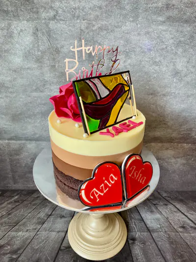 Tall triple-chocolate mousse cake topped with a multicoloured stained-glass artwork recreated in edible isomalt, a large pink sugar flower and two translucent red isomalt hearts.